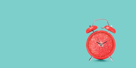 Juicy grapefruit on alarm clock dial against turquoise background. Creative poster with space for text, banner design