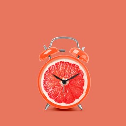 Juicy grapefruit on alarm clock dial against dark coral background. Creative poster