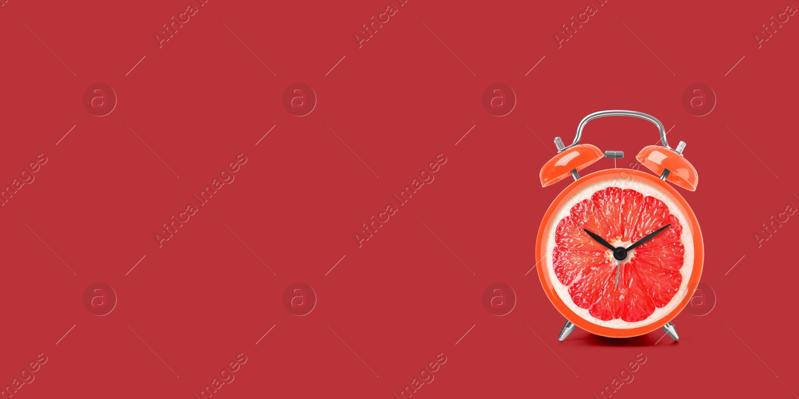 Image of Juicy grapefruit on alarm clock dial against red background. Creative poster with space for text, banner design