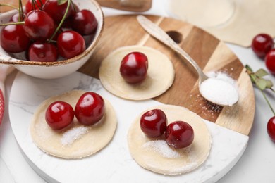 Photo of Process of making dumplings (varenyky) with cherries. Raw dough and ingredients on white tiled table