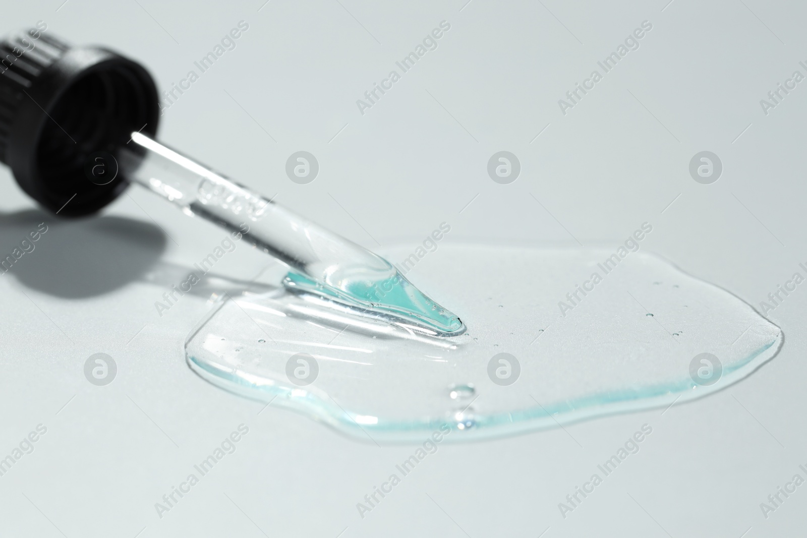 Photo of Pipette with cosmetic serum on light background, closeup