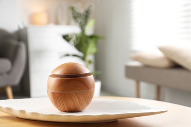 Photo of Essential oil diffuser on wooden table at home, space for text