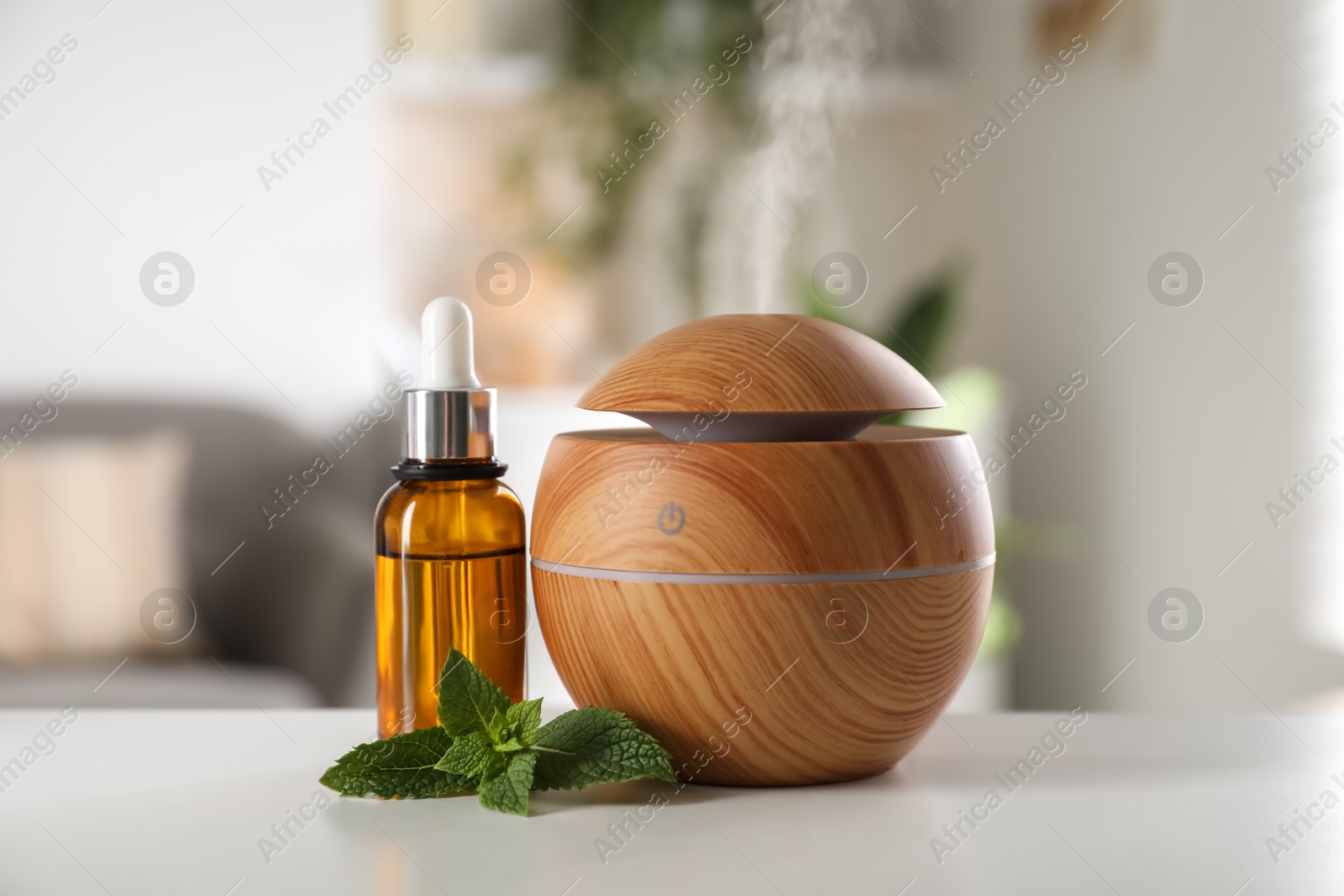 Photo of Essential oil diffuser, cosmetic product and mint on white table at home