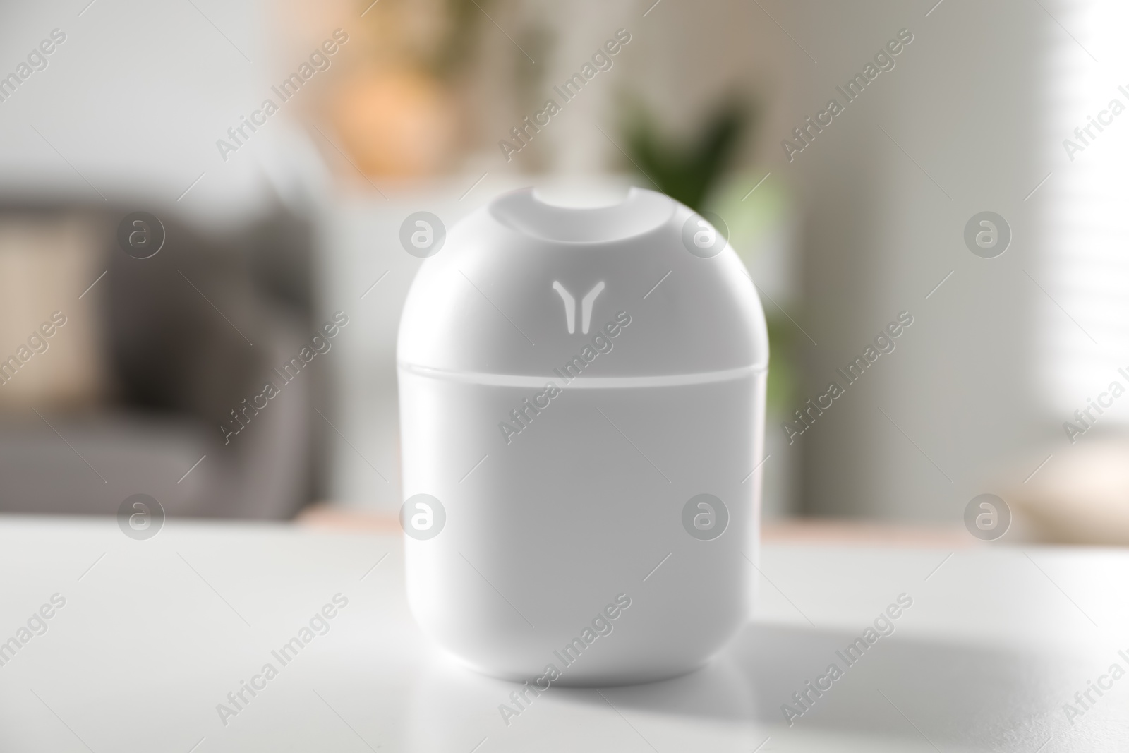 Photo of Essential oil diffuser on white table at home