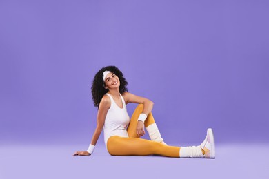 Happy woman in sportswear on purple background