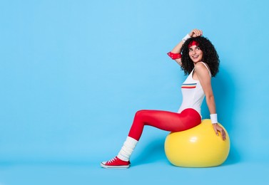 Aerobics. Happy woman with fitness ball on light blue background, space for text