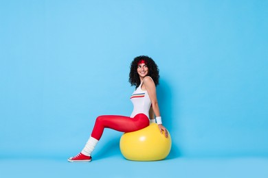 Photo of Aerobics. Happy woman with fitness ball on light blue background