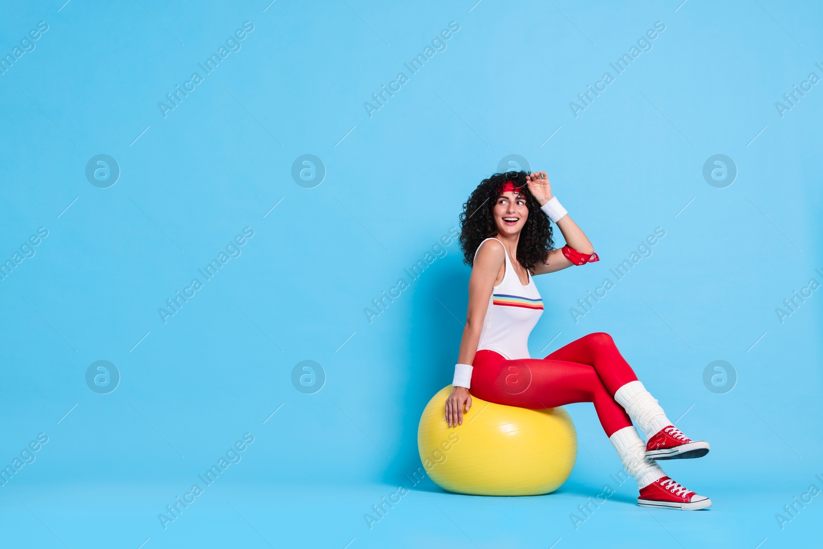 Photo of Aerobics. Happy woman with fitness ball on light blue background, space for text