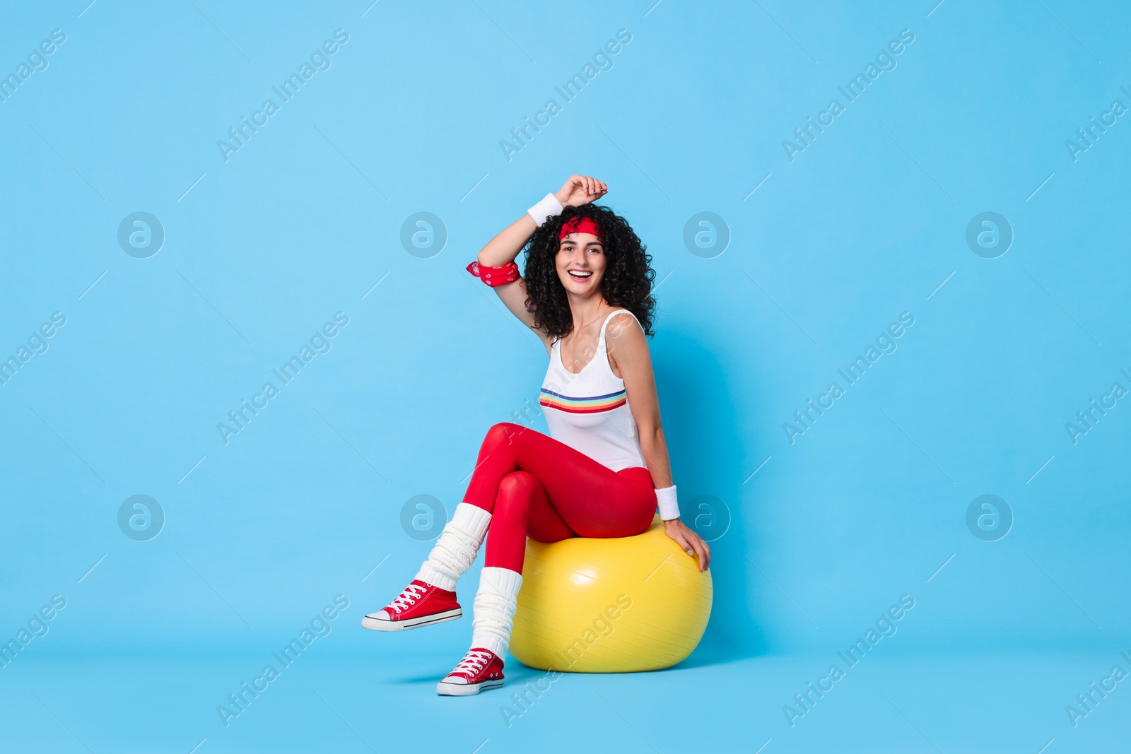 Photo of Aerobics. Happy woman with fitness ball on light blue background