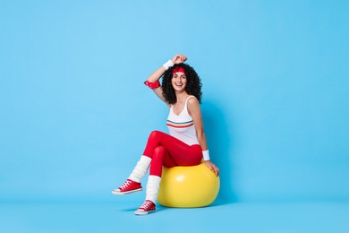 Photo of Aerobics. Happy woman with fitness ball on light blue background