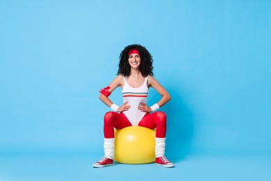 Photo of Aerobics. Happy woman with fitness ball on light blue background