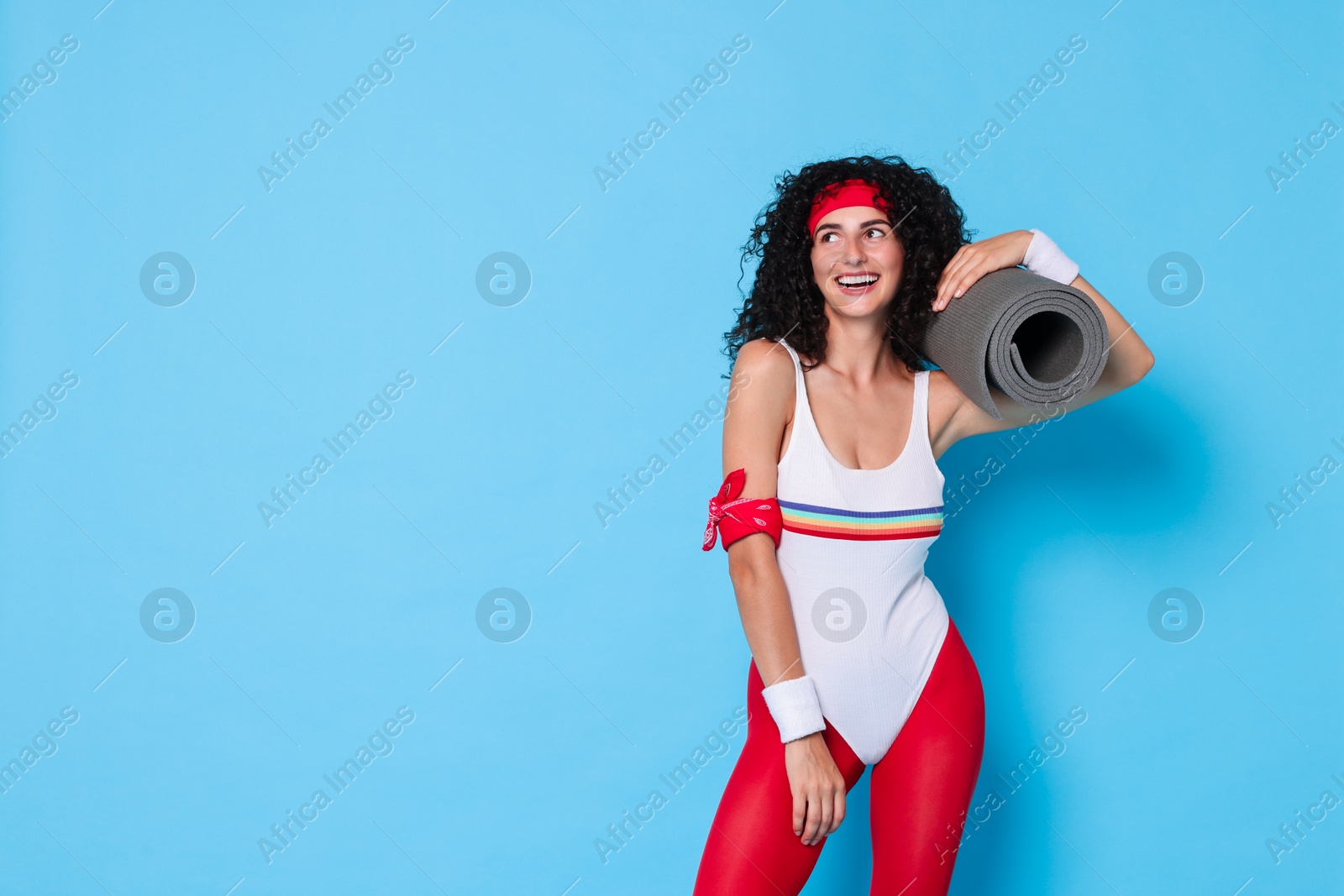 Photo of Aerobics. Happy woman with fitness mat on light blue background, space for text