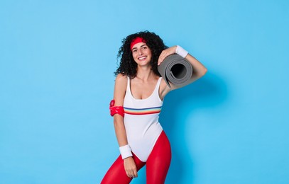 Aerobics. Happy woman with fitness mat on light blue background, space for text