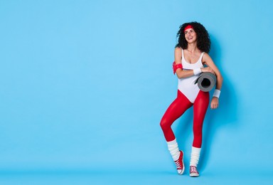 Aerobics. Happy woman with fitness mat on light blue background, space for text