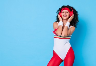 Aerobics. Happy woman in headphones on light blue background, space for text