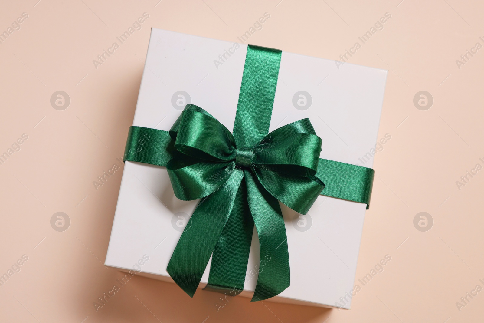 Photo of Gift box with bow on beige background, top view