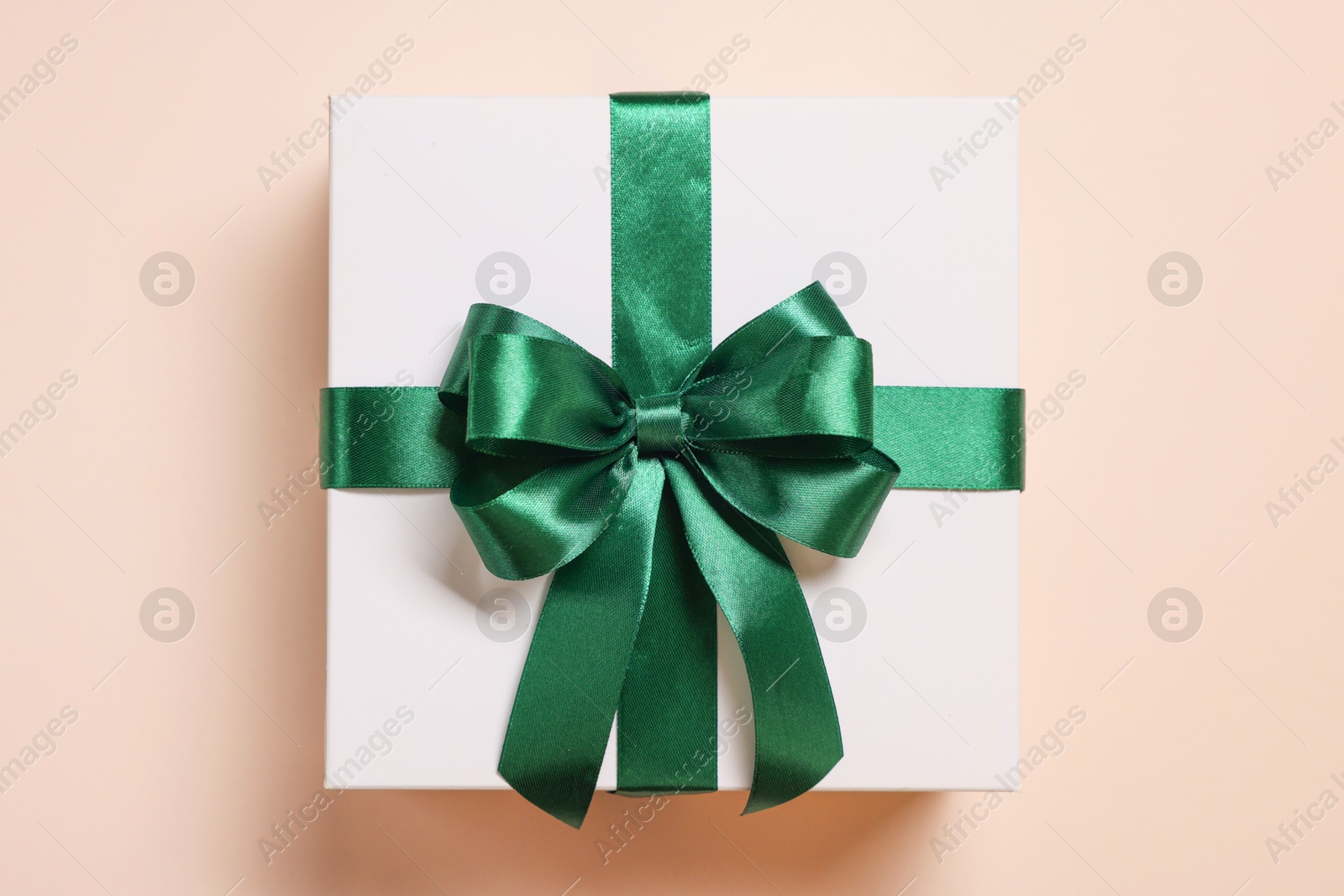 Photo of Gift box with bow on beige background, top view