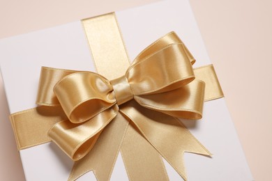 Photo of Gift box with bow on beige background, closeup