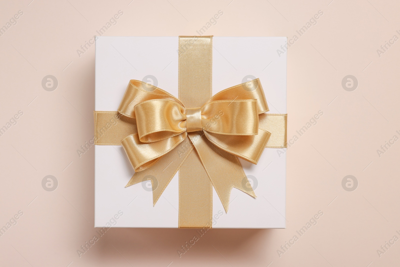 Photo of Gift box with bow on beige background, top view