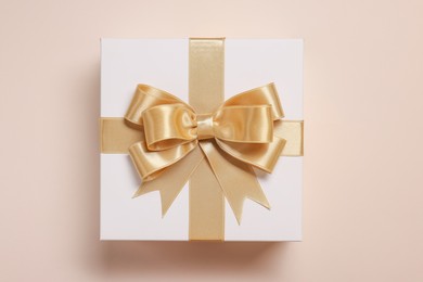 Photo of Gift box with bow on beige background, top view