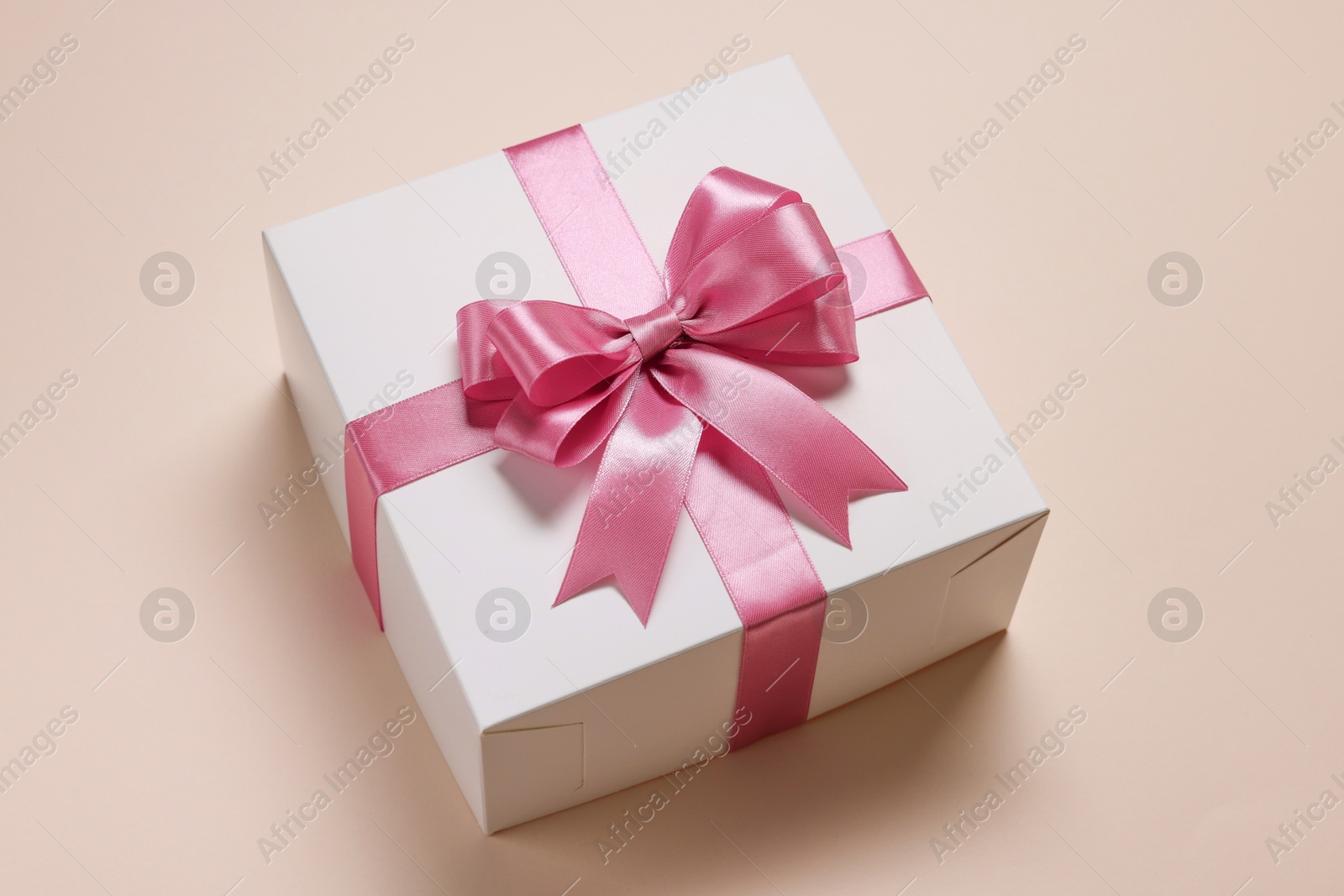 Photo of Gift box with bow on beige background