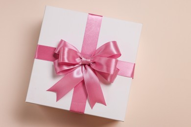 Photo of Gift box with bow on beige background, top view