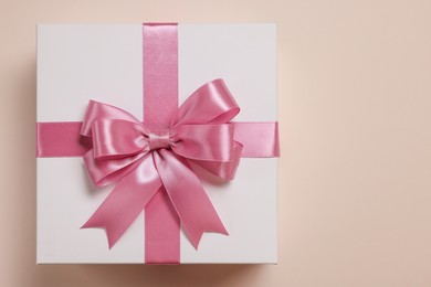 Photo of Gift box with bow on beige background, top view. Space for text