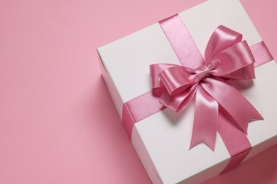 Gift box with bow on dusty pink background, closeup