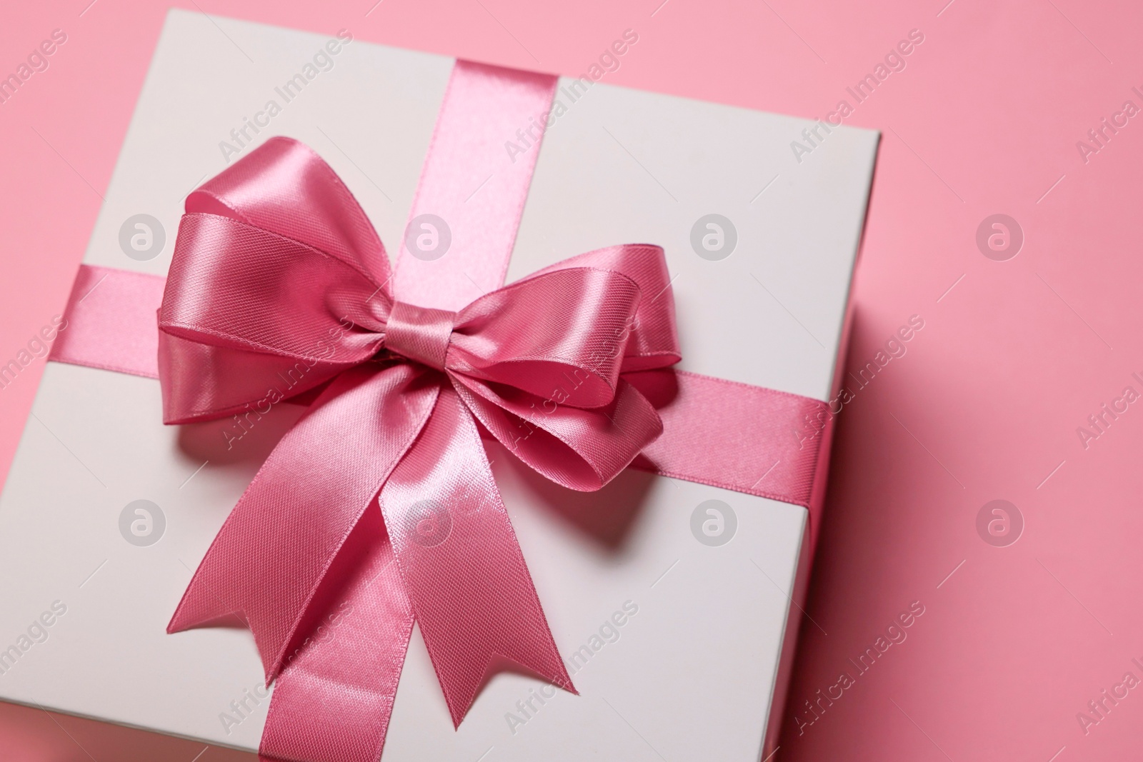 Photo of Gift box with bow on dusty pink background, closeup