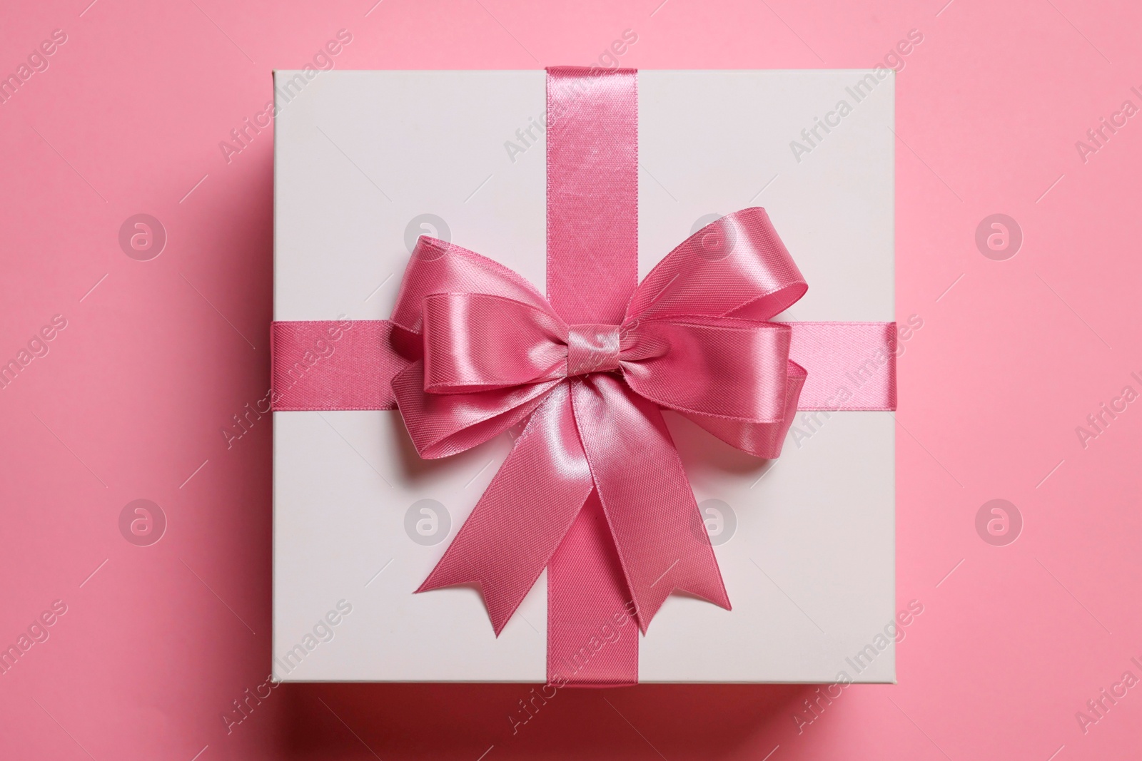 Photo of Gift box with bow on dusty pink background, top view