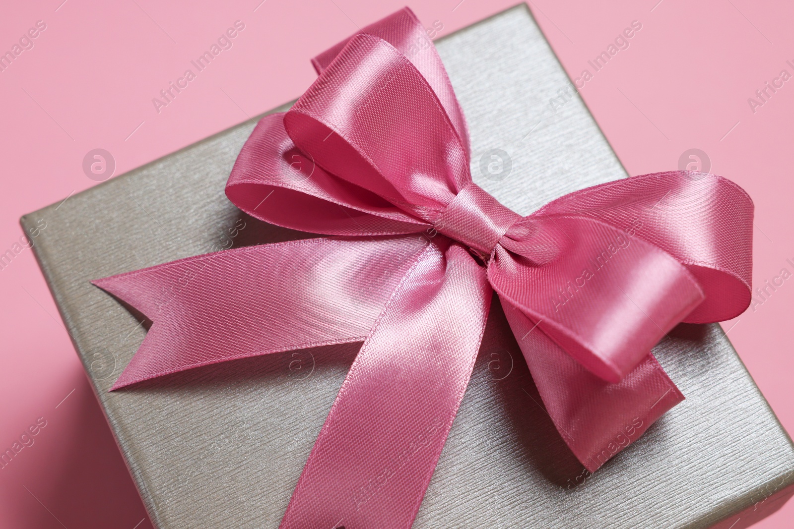 Photo of Gift box with bow on dusty pink background, closeup