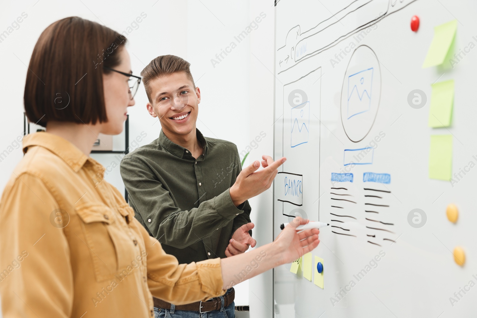 Photo of Developing UI design. Man and woman drawing website wireframe on whiteboard indoors