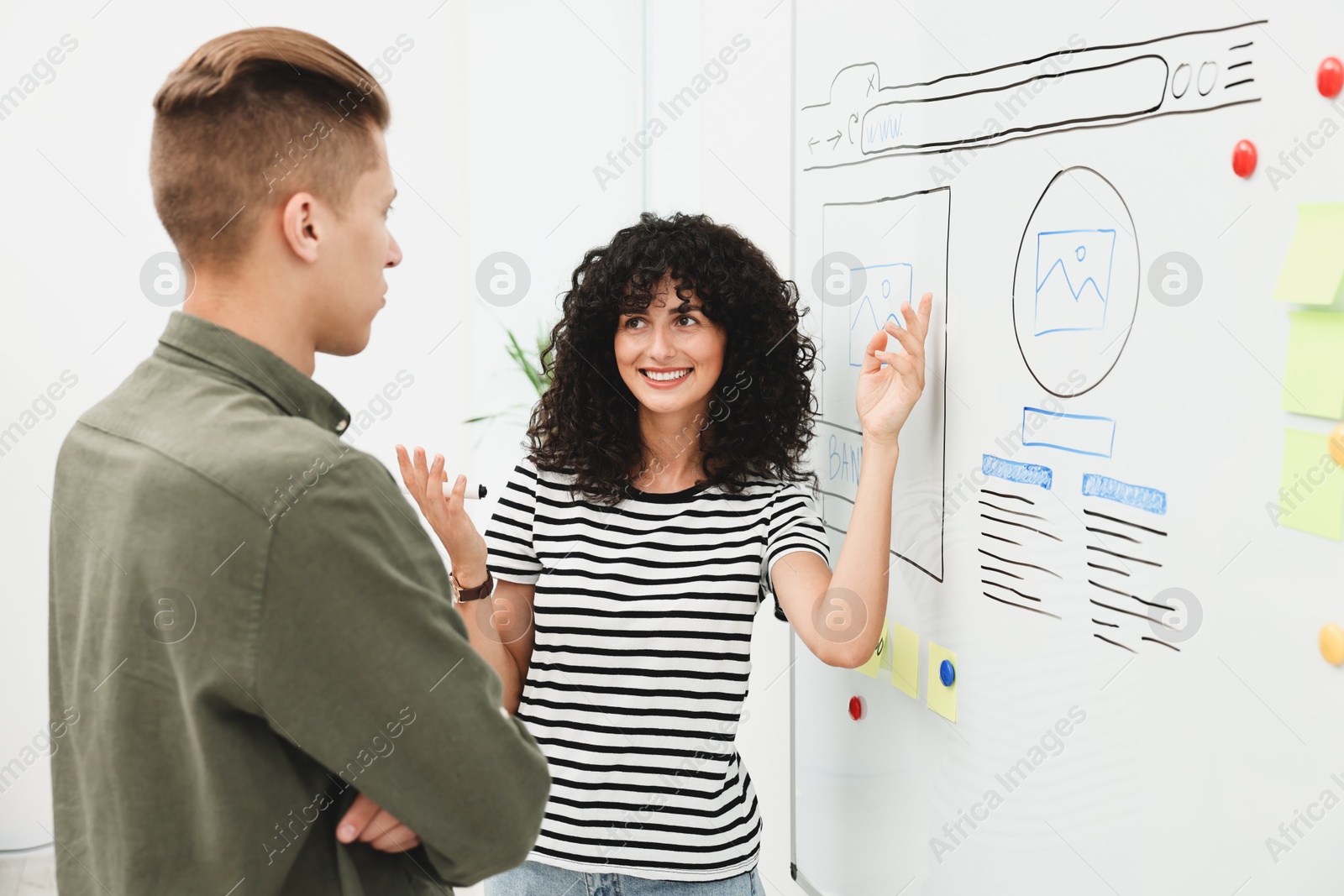 Photo of Developing UI design. Man and woman drawing website wireframe on whiteboard indoors