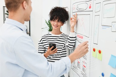 Developing UI design. Man and woman drawing website wireframe on whiteboard indoors