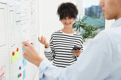 Developing UI design. Man and woman drawing website wireframe on whiteboard indoors