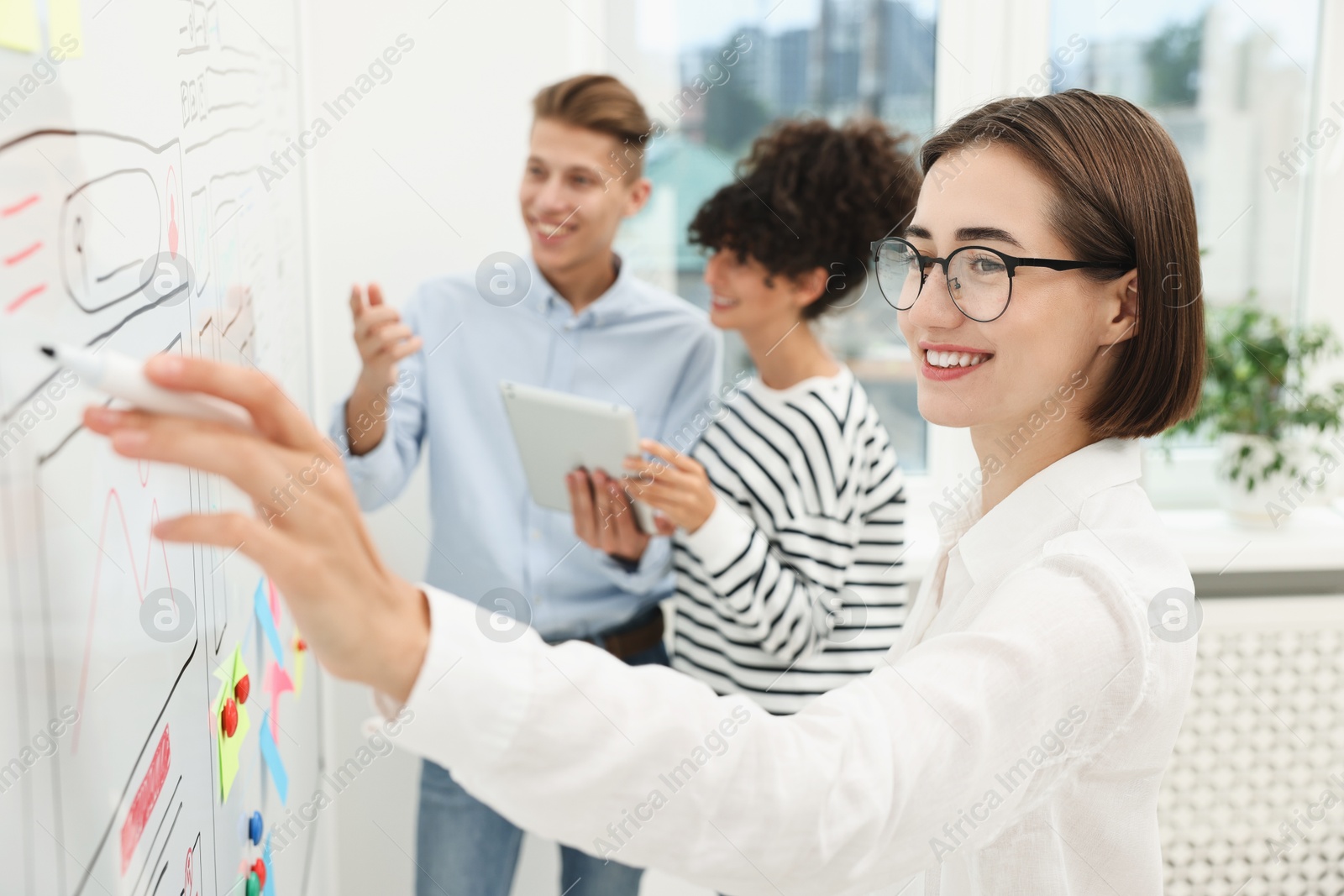 Photo of Developing UI design. People drawing website wireframe on whiteboard indoors