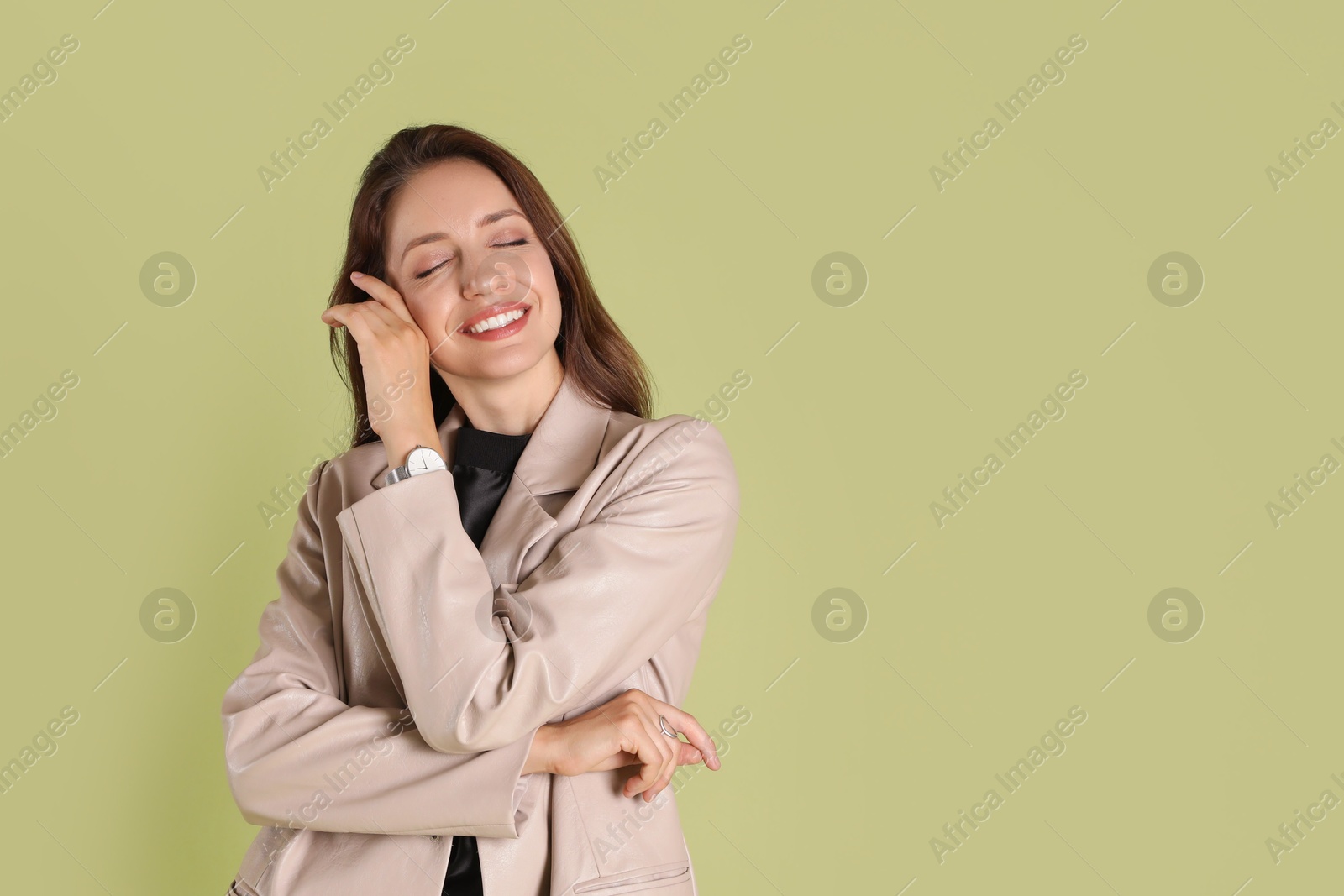 Photo of Beautiful woman in stylish beige jacket on olive background, space for text