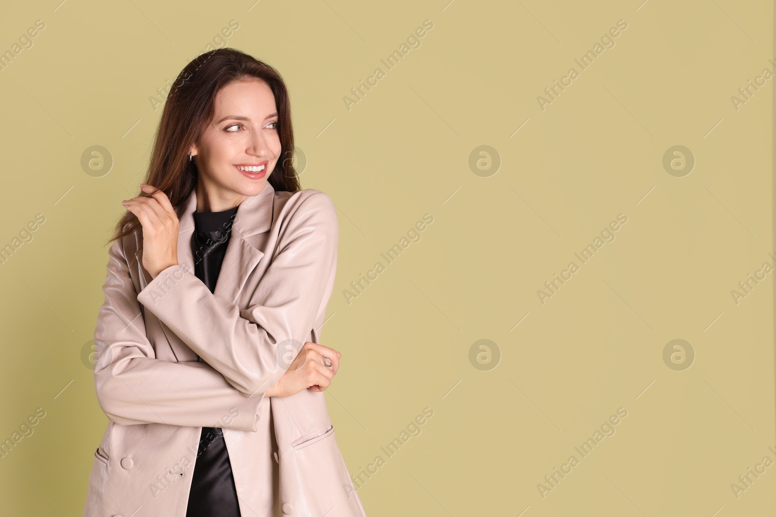 Photo of Beautiful woman in stylish beige jacket on olive background, space for text