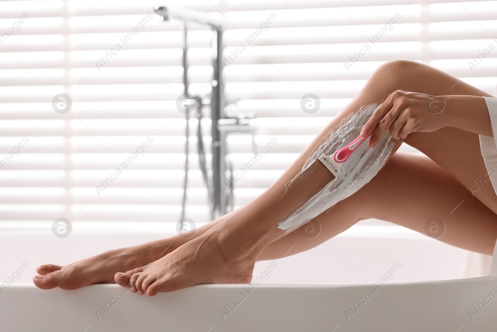 Photo of Woman shaving leg in bathtub indoors, closeup. Space for text