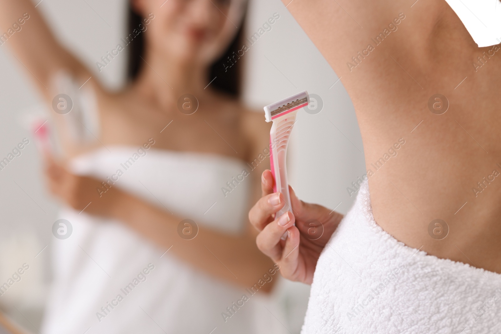 Photo of Woman shaving armpit near mirror indoors, closeup. Space for text