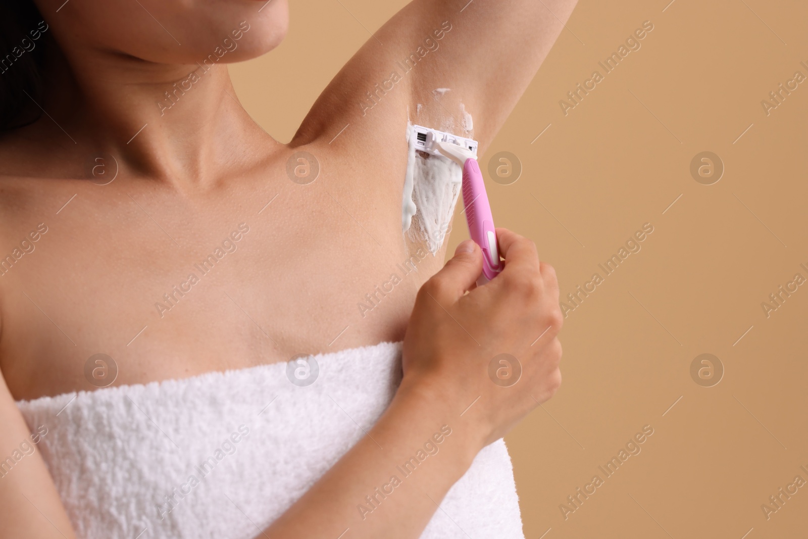 Photo of Woman shaving armpit on beige background, closeup. Space for text