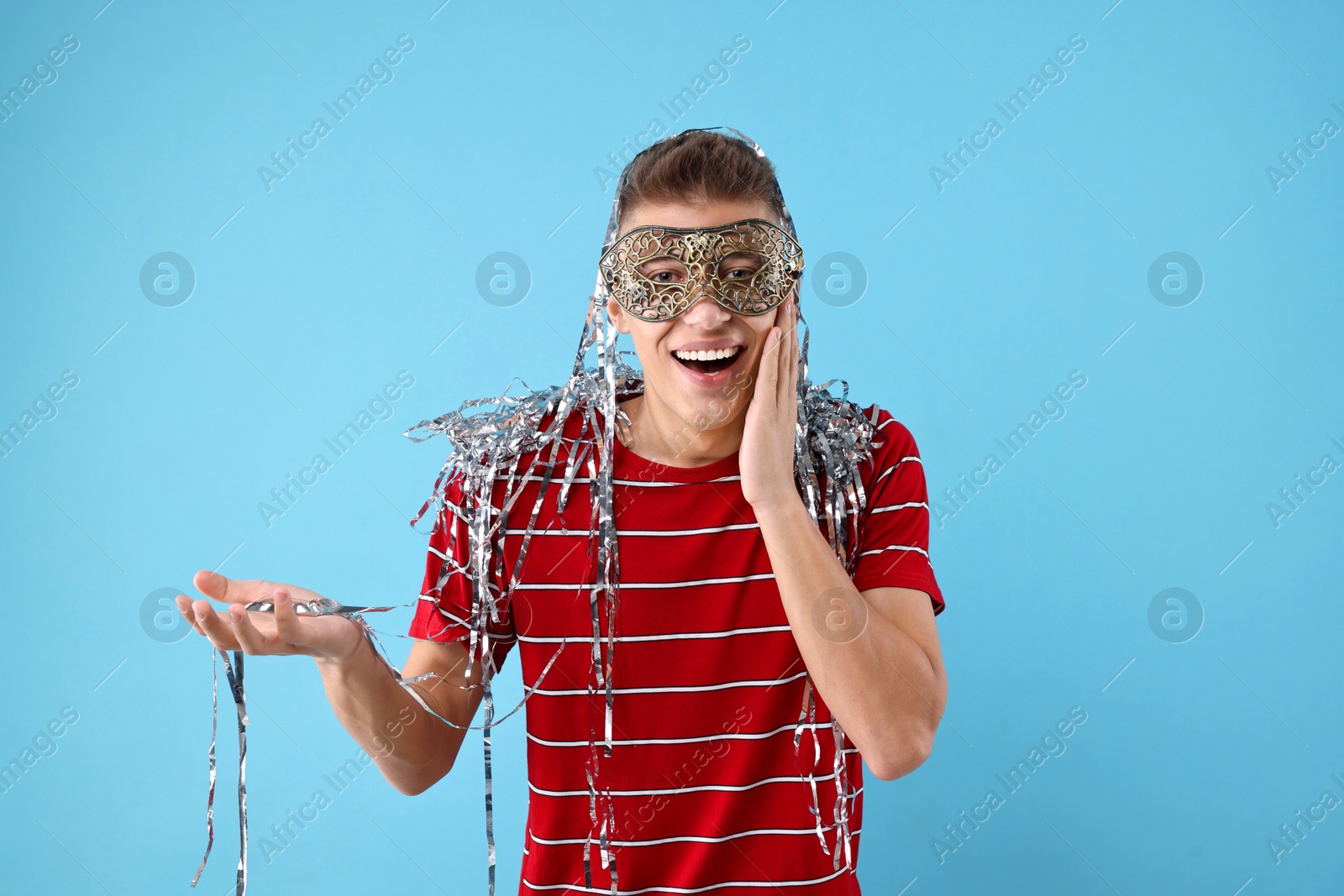 Photo of Charming young man wearing carnival mask on light blue background