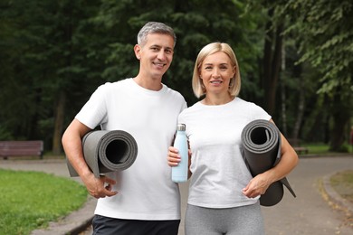 Happy couple with yoga mats in park