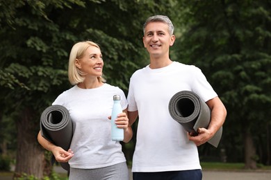 Happy couple with yoga mats in park