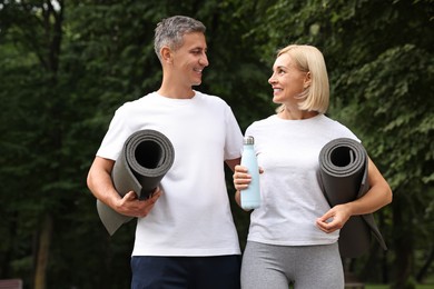 Happy couple with yoga mats in park