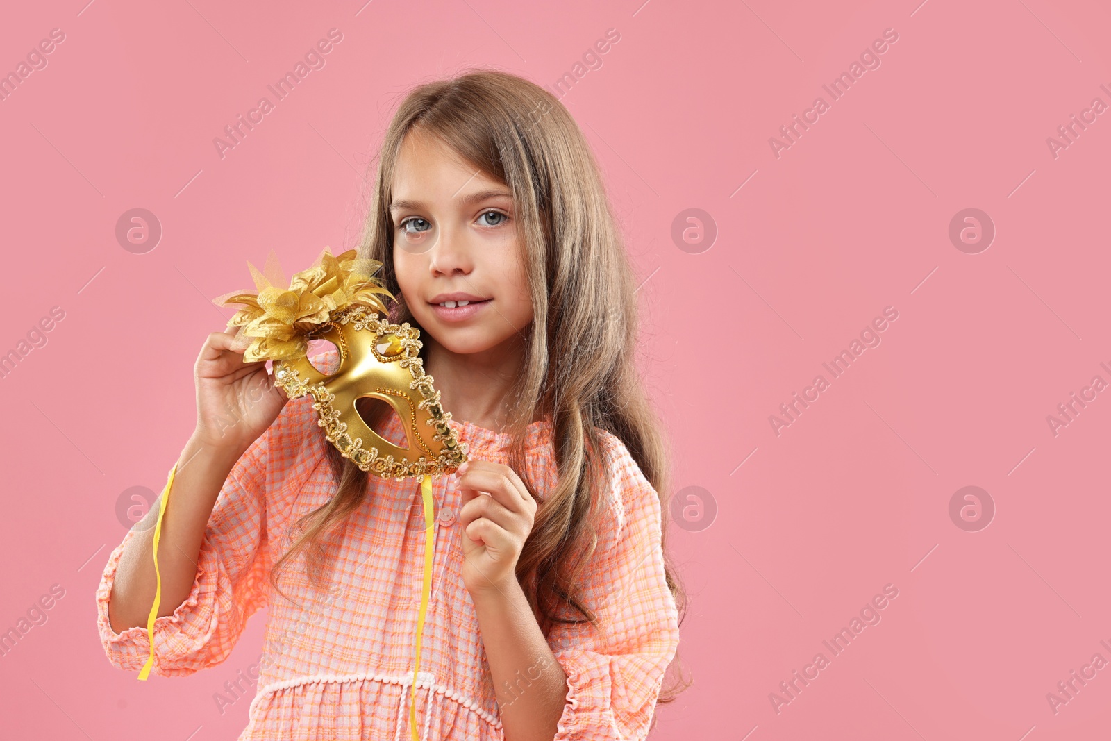 Photo of Cute girl with carnival mask on pink background, space for text