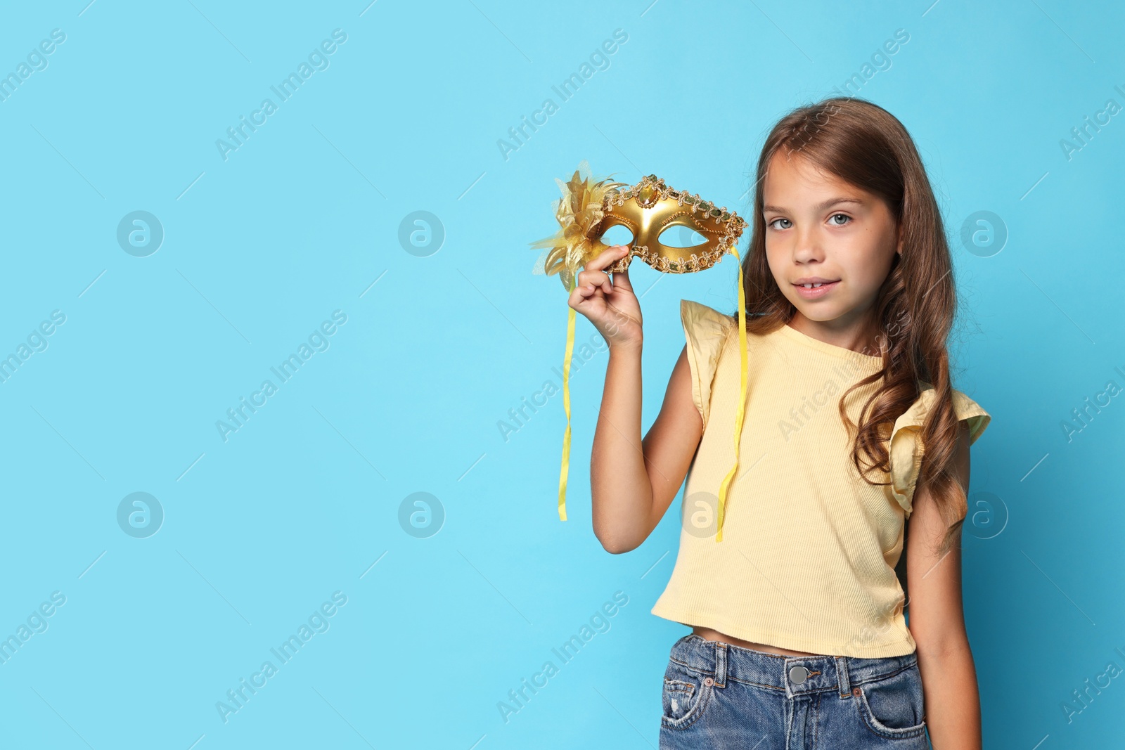 Photo of Cute girl with carnival mask on light blue background. Space for text