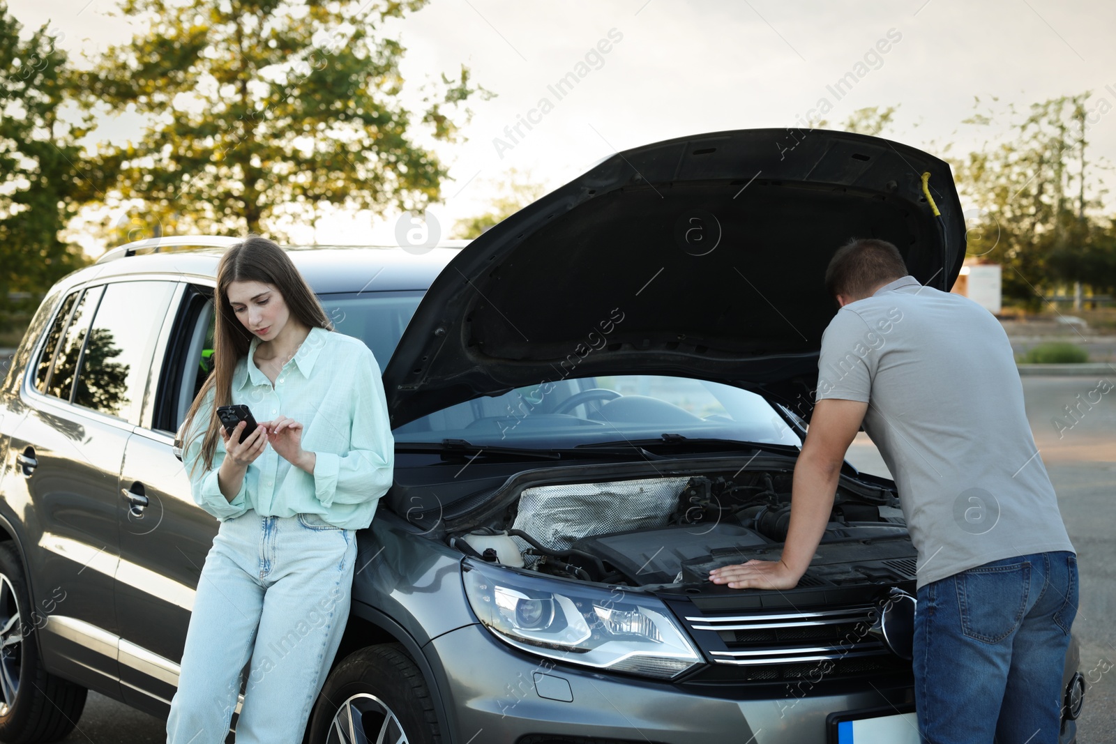 Photo of Man and woman near broken car outdoors