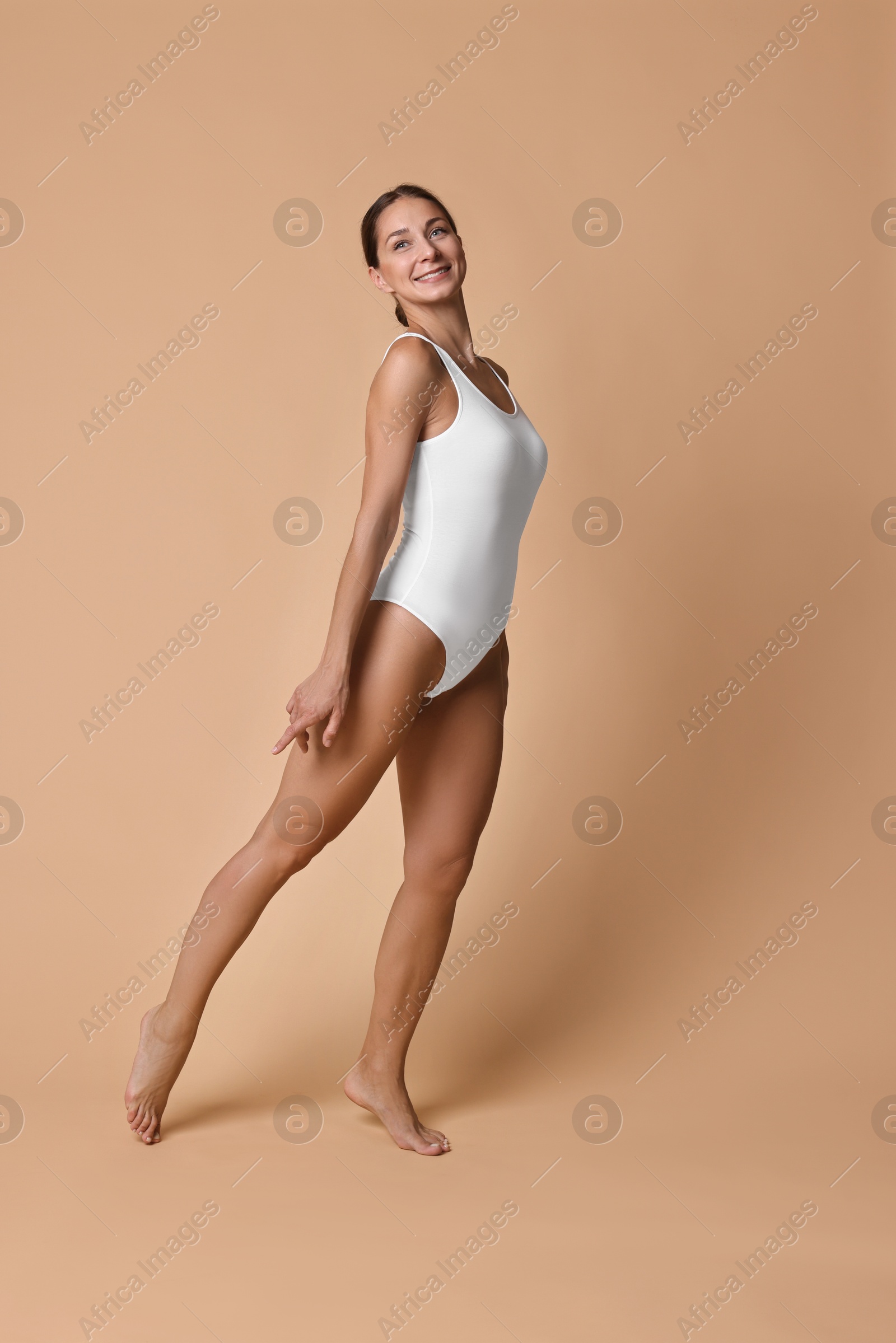 Photo of Smiling woman with perfect skin posing on beige background. Body care