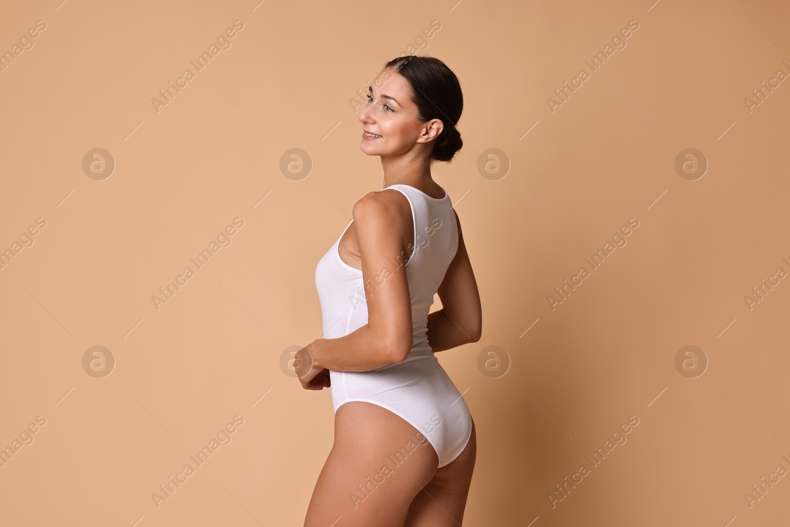 Photo of Smiling woman with perfect skin posing on beige background. Body care